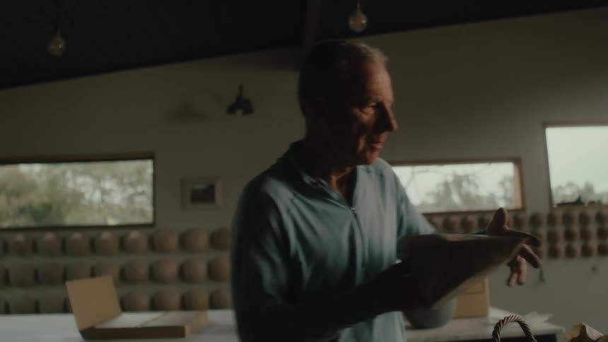 A man packages a loaf of yeast bread in a bakery