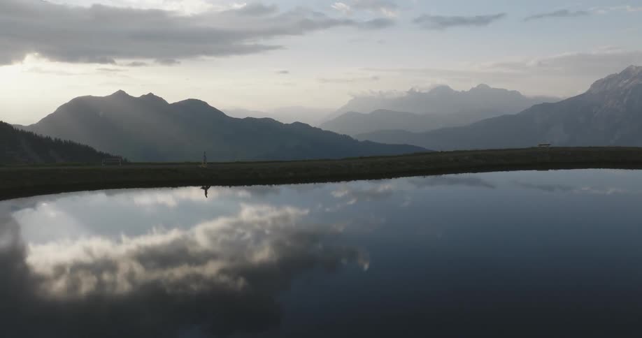 A person walking near a serene alpine lake nestled among towering mountains
