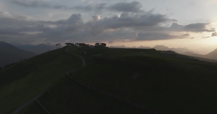 A ball of sunlight moves along the path of a stream beside silhouetted houses on top of a hill