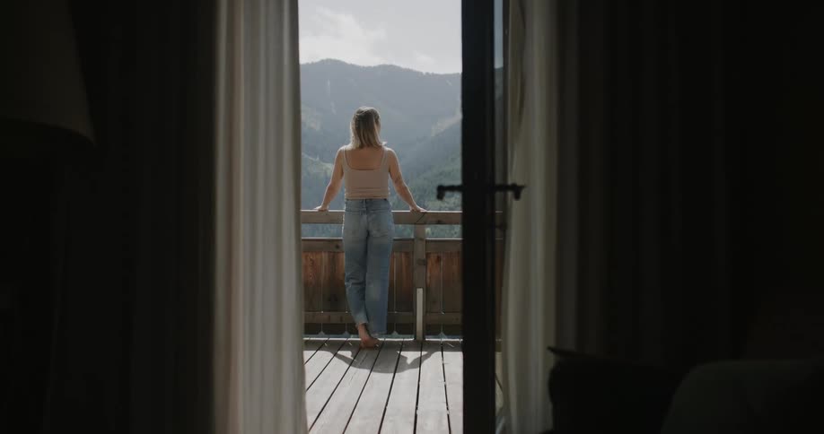 Blonde woman on the balcony enjoying the view of the mountain range
