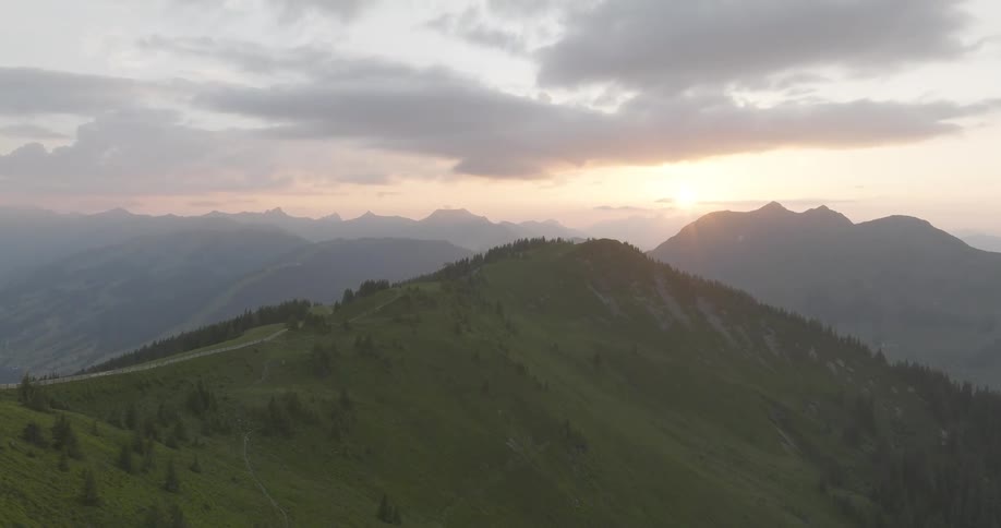 Landscape of mountain ranges with a reddish sunset on the horizon