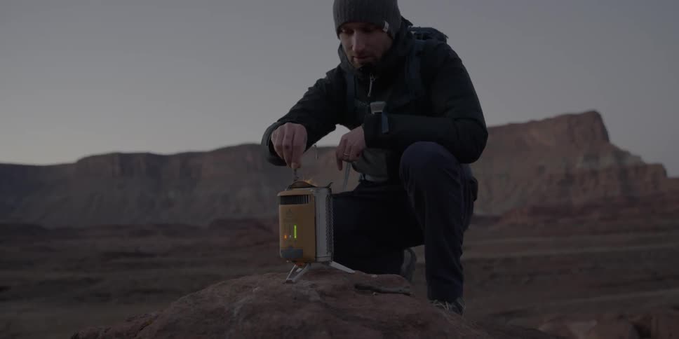 Man stirring a fire in a lantern in the wilderness