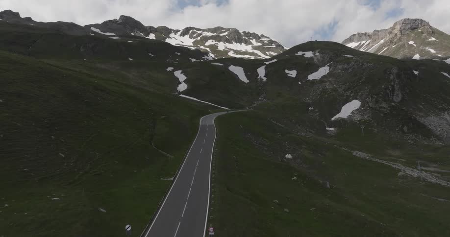 Aerial view over a mountain pass highway with snowy peaks in the background