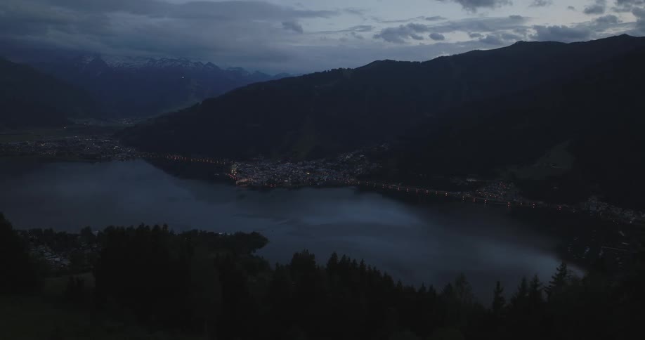 A mountainous landscape with a lake and an illuminated city skyline
