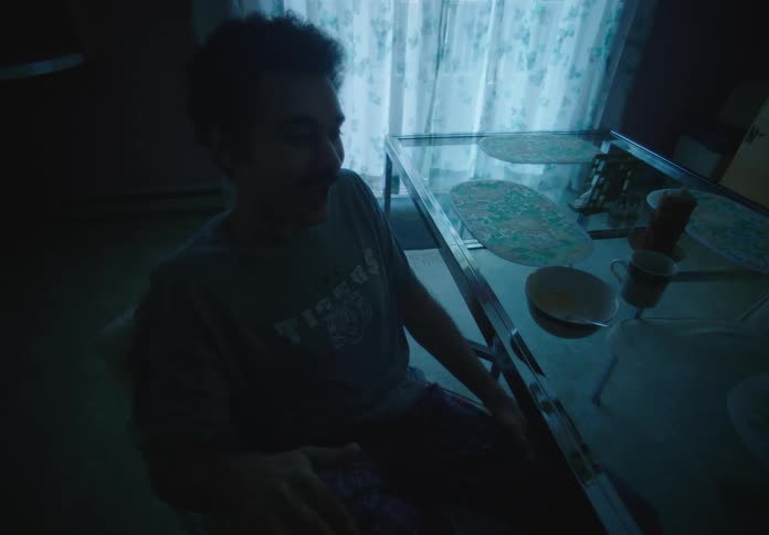 Silhouette of a man sitting on a dimly lit room near a dining table