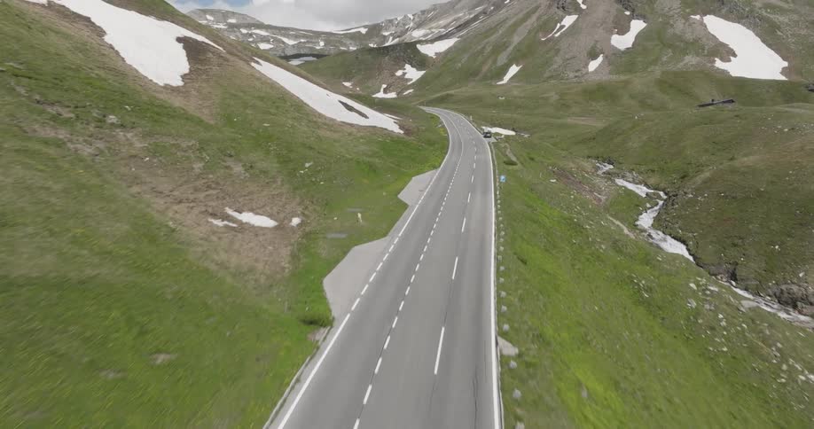 Aerial of a highway running through a mountain range on a mostly cloudy day