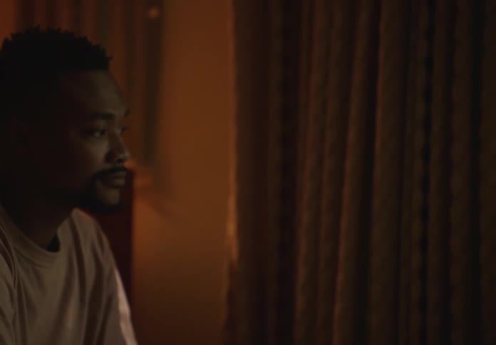 A man sits quietly gazing thoughtfully out of a window in a warmly lit room