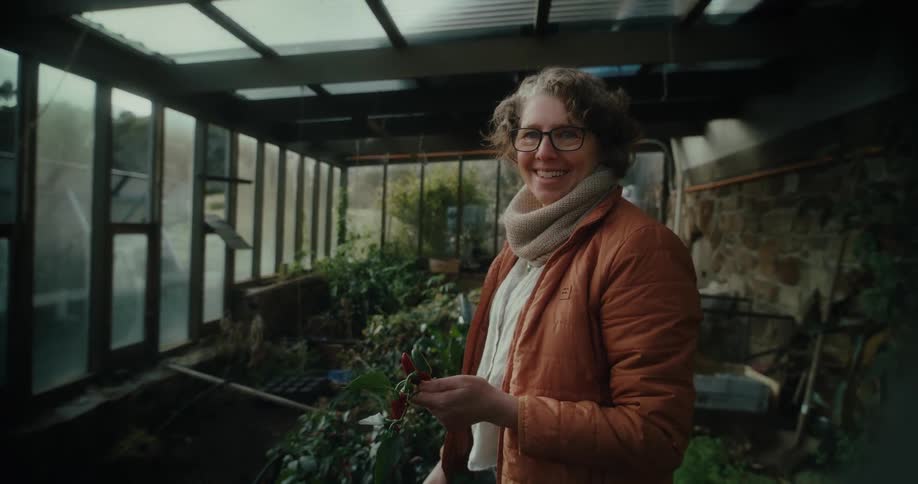 Smiling woman holding a leafy vegetable in a greenhouse