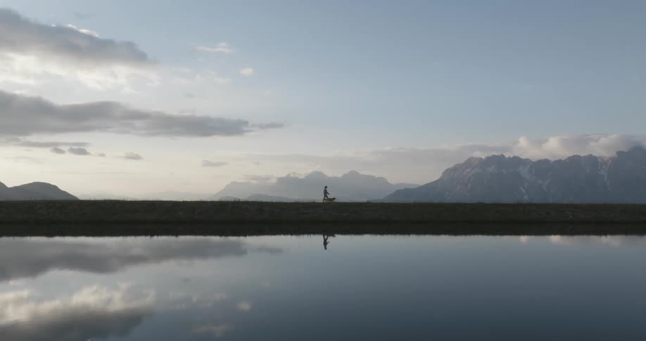 A person is walking their dog past the water