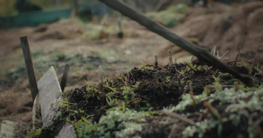 A gardening tool moving the dark rich soil on a garden bed