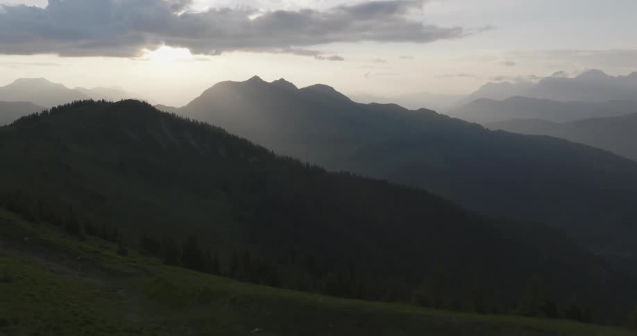 A woman walking her dog near a lake atop the mountains at sunset