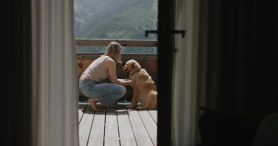 Blonde woman playing and petting her golden dog