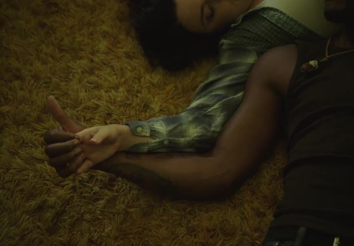 Couple lying on a rug holding hands and caressing each other