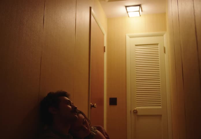 Man and woman sitting in a hallway holding each other