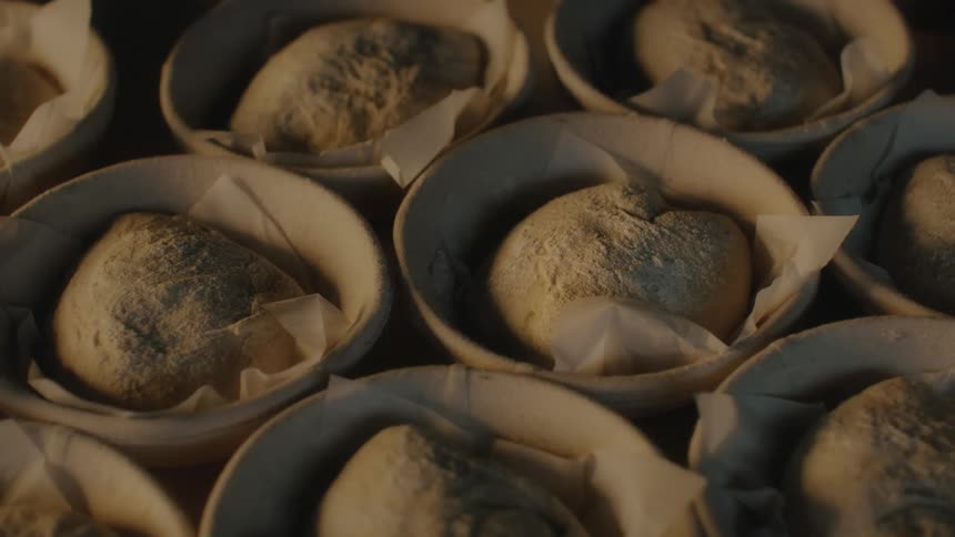 Pieces of bread sitting on paper inside small bowls