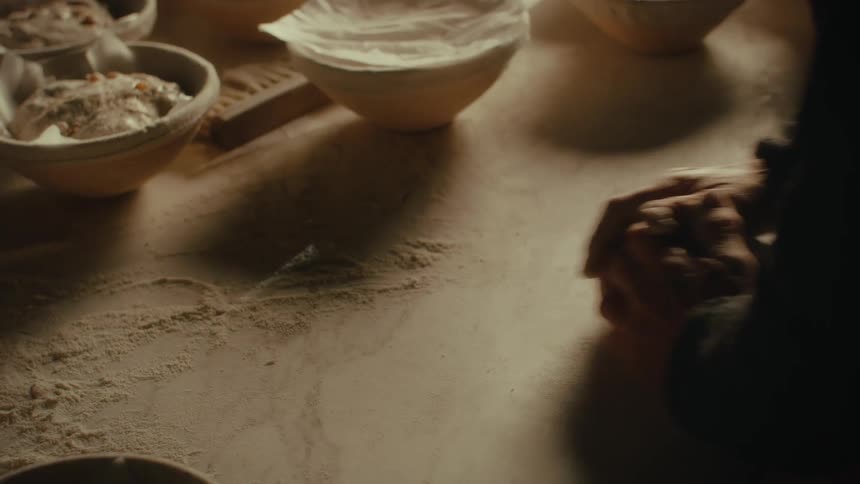Closeup of a persons hands working with flour on a wooden surface kneading dough on a rustic ambience