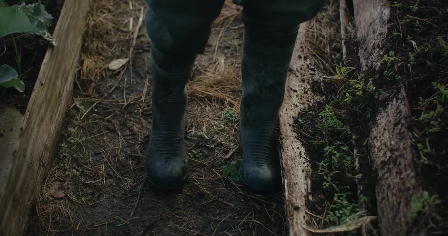 Feet of a person with boots while in a vegetable garden