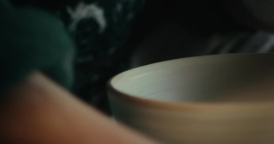 A closeup of a persons hands carefully shaping a clay bowl on a pottery wheel