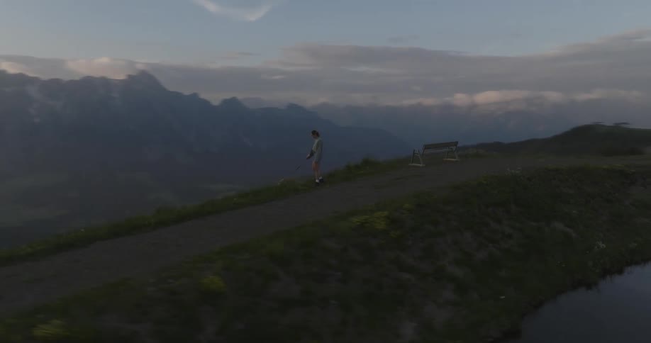 Landscape of mountains and a lake with a person walking with their dog