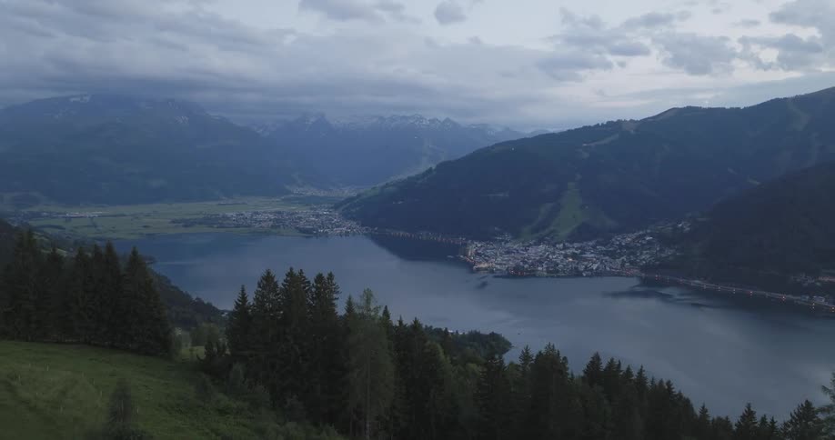 Aerial landscape of hills and mountains surrounded by a lake in a city in the background