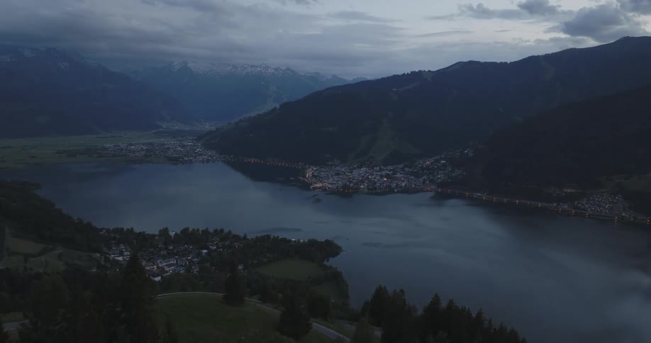 A town nestled by the side of a serene lake with mountains in the background