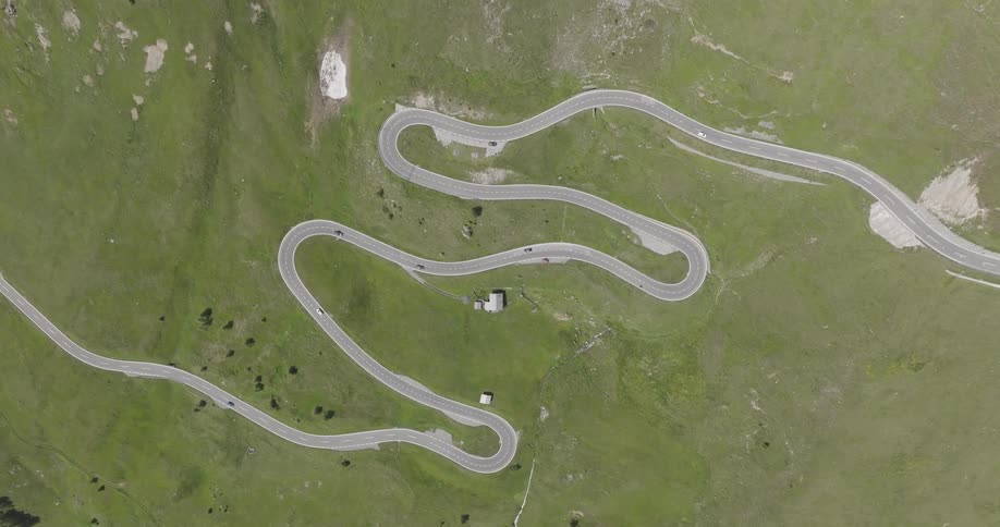 Aerial view of cars driving down a winding road with multiple hairpin turns