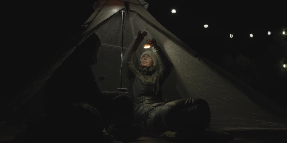 Two people sitting in a tent at night