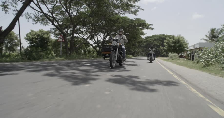 Two people ride motorcycles on a city street