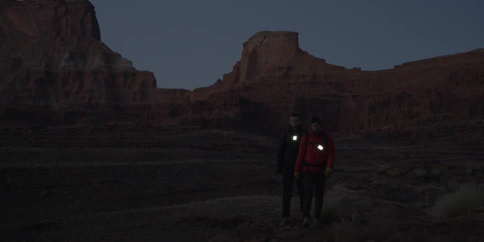 Hikers walk through a desert area at dusk