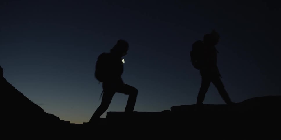 Silhouette of two hikers walking a trail at sunset