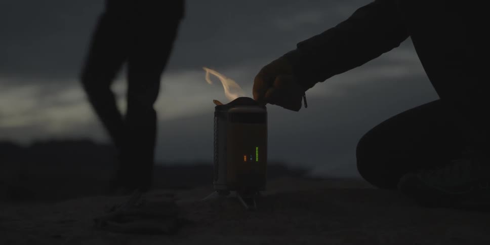 A person pokes a fire in a silver box