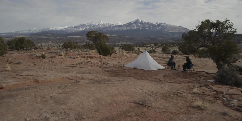 Campers sit next to their tent in the wilderness