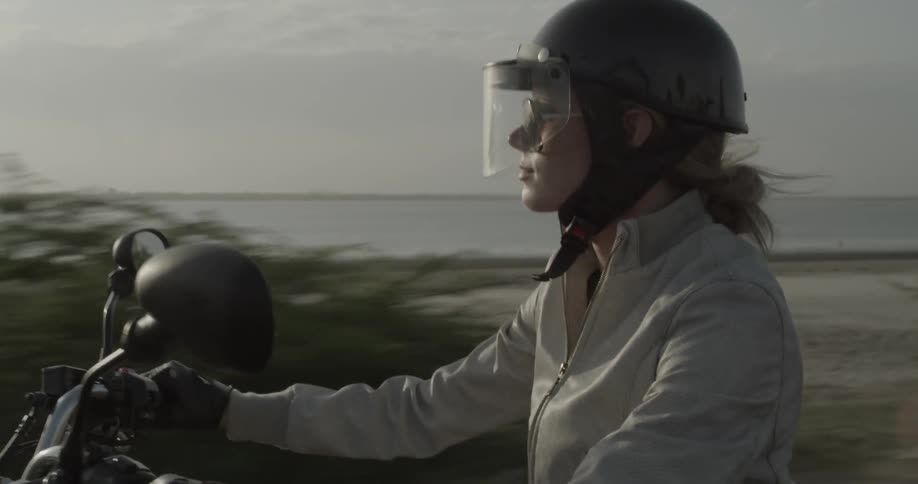 A woman is riding a motorcycle on a cloudy day