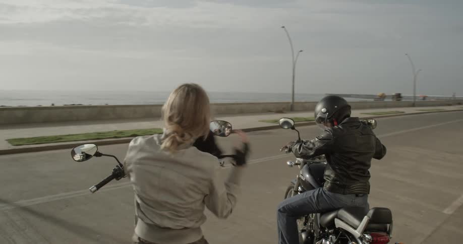 A woman removes her helmet after parking her motorcycle