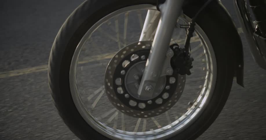 View of motorcycle wheel turning on pavement
