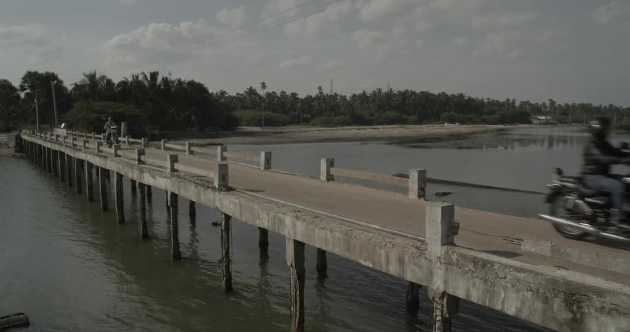 People riding motorcycles ride on a dock over the water