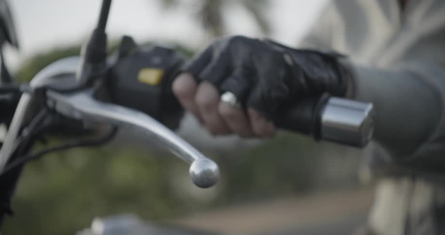 A man grips the handlebar of a motorcycle as he rides