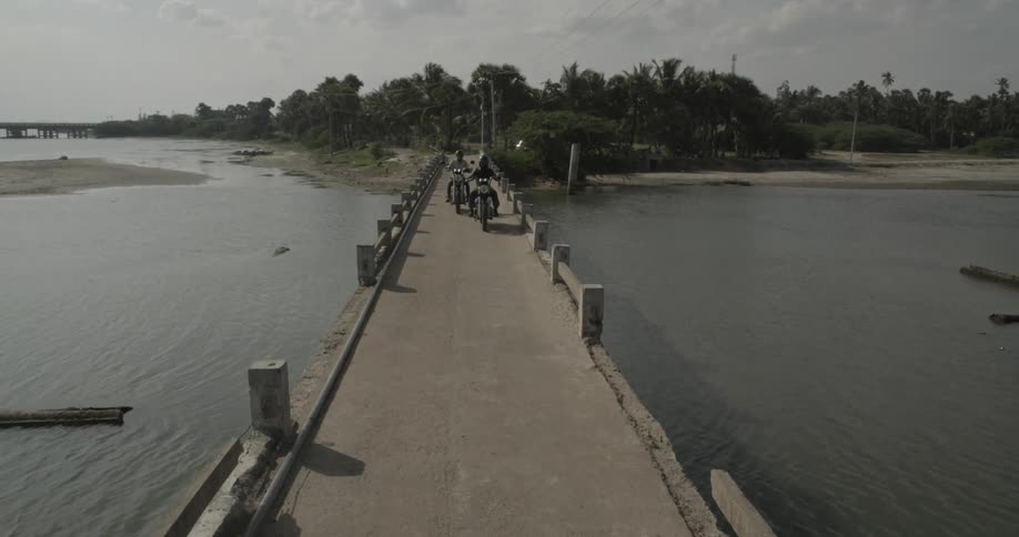 Two bikers are riding along a dock towards the camera