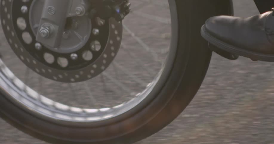 A motorcycle wheel is turning on the pavement