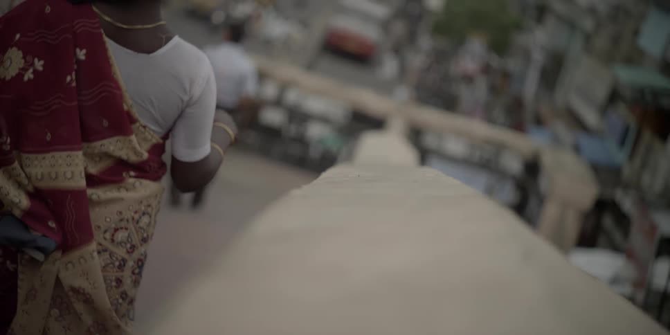 A woman rubs a railing and walks down a street