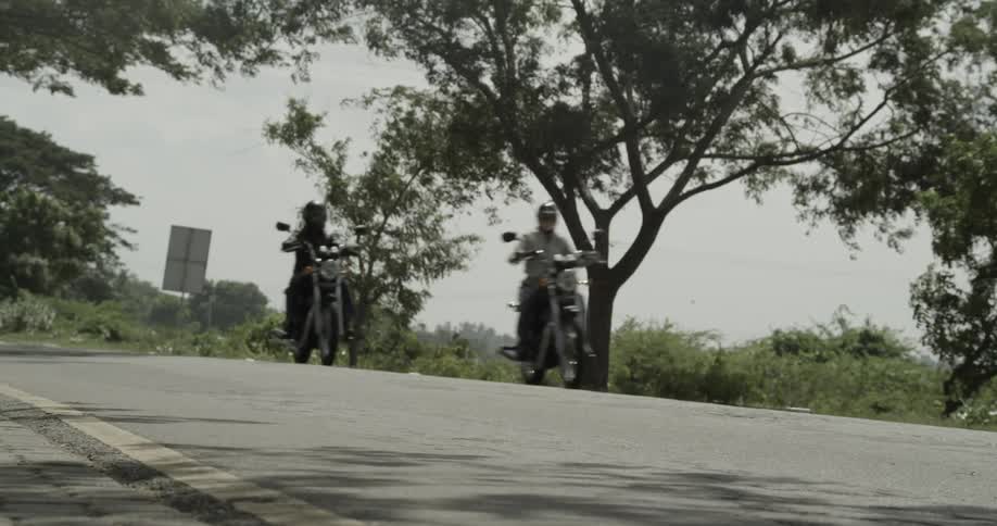 Two motorcycles drive down the road