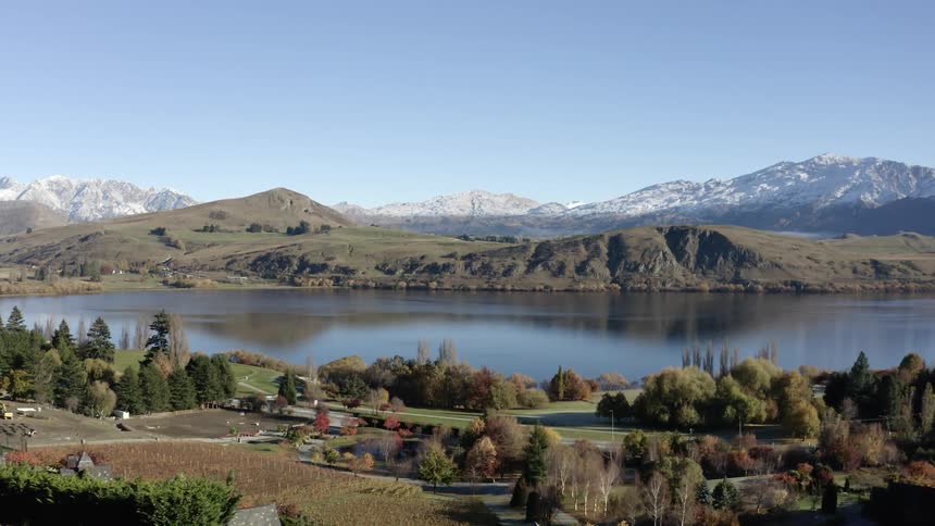 A serene landscape featuring a lake surrounded by lush greenery and snowcapped mountains in the distance