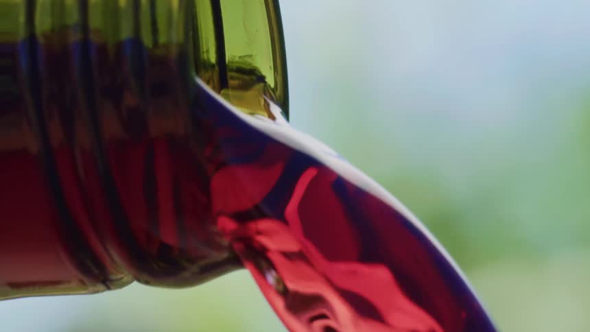 A close up of liquid being poured from a bottle with a blurred background