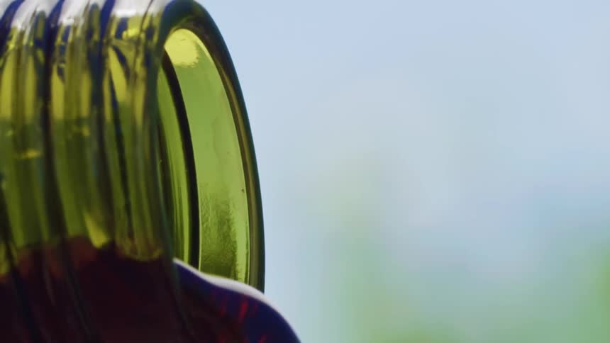Red wine flows from the mouth of a green wine bottle