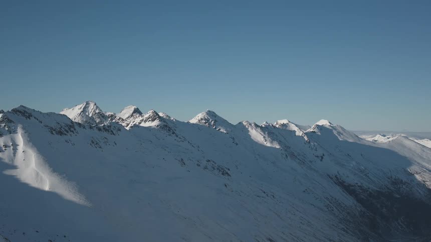 The shines low on a snow covered mountain range