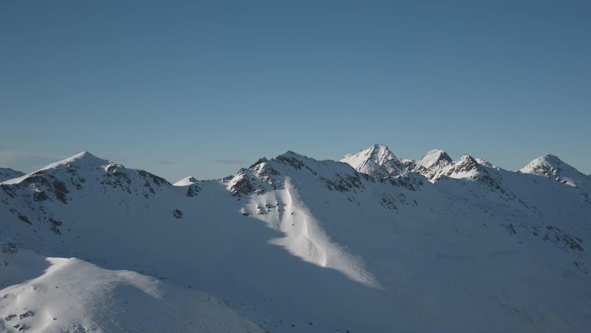 A snow covered mountain range landscape under a clear blue sky