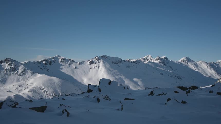 A large and rocky mountain range buried in deep snow