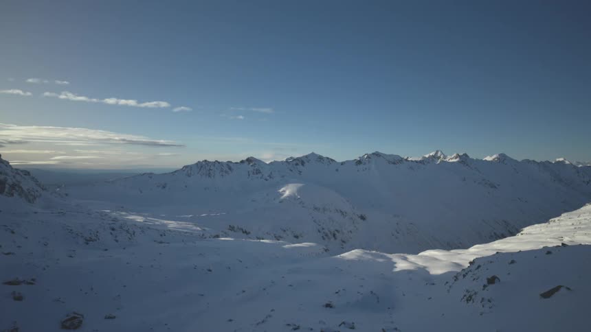 Snowcovered mountains under a mostly clear blue sky