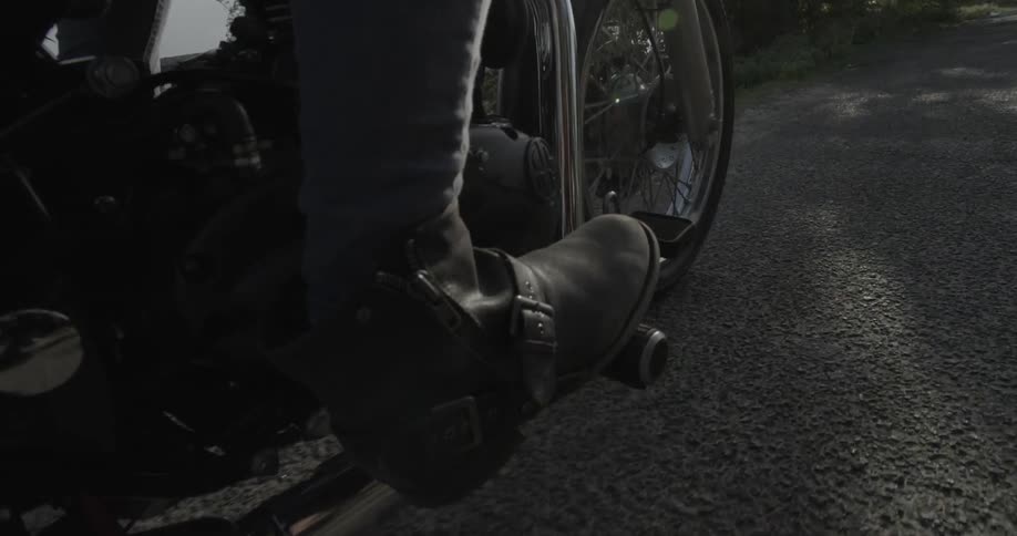 Extreme close-up of a motorcyclist's boot as he's riding on a trail