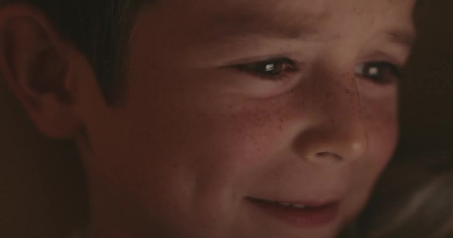 A young child smiles and laughs while watching something